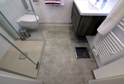 Blick im kleinen Badezimmer auf den grau gefliesten Boden.JPG
