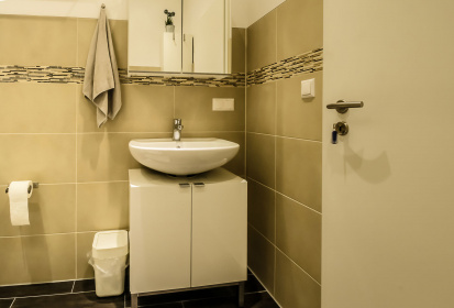 Badezimmer mit ocker Fliesen Blick auf Wschbecken mit Unterschrank.jpg