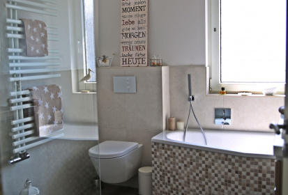 Tageslichtbad mit Mosaikbadewanne, grauen rechteckigen Fliesen, Handtuchhalter Heizung und begehbare Dusche.jpg