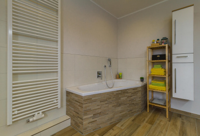 Abgeschraegte Badewanne fuer mehr Platz und daneben Badezimmermoebel aus Holz.jpg